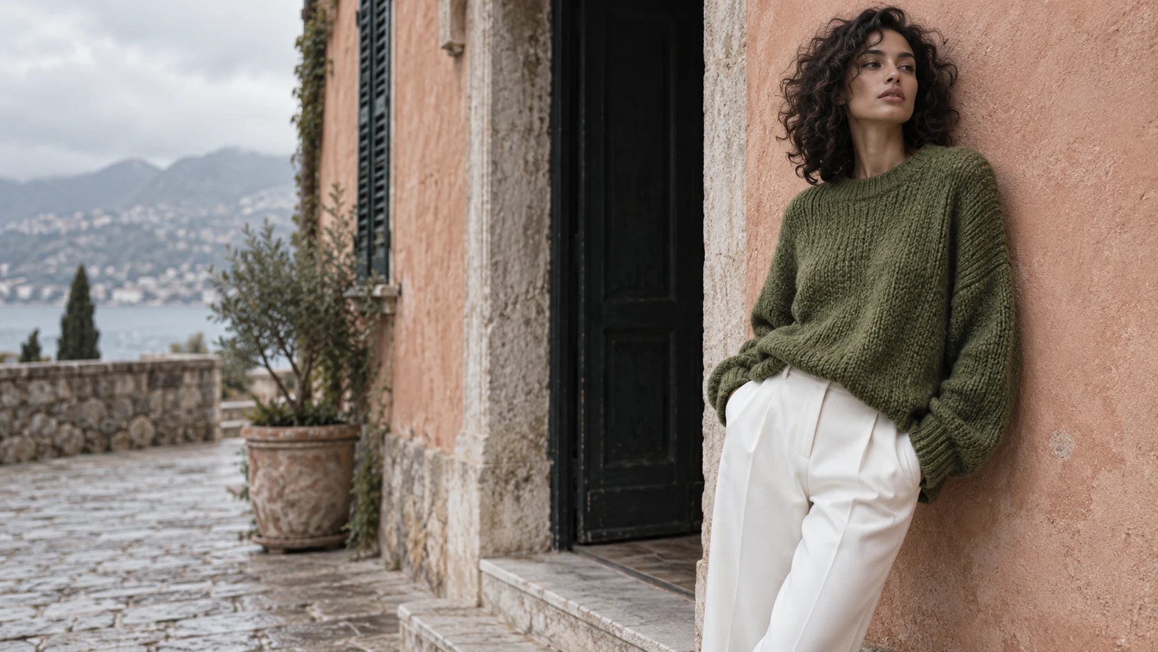 Knitwear campaign illustration: moss-green sweater against peach architecture