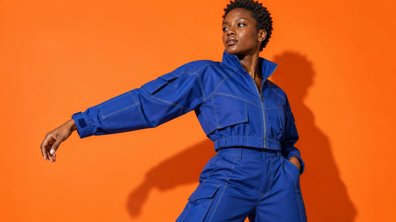 Fashion campaign illustration: cobalt utility jacket showing sleeve panels and topstitching against orange